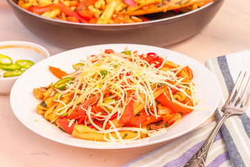 Italian food - Pasta with red pepper and parmesan on a white plate on a rustic light table