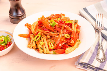 Italian food - Pasta with red pepper and parmesan on a white plate on a rustic light table