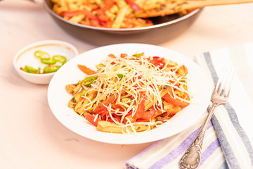 Italian food - Pasta with red pepper and parmesan on a white plate on a rustic light table