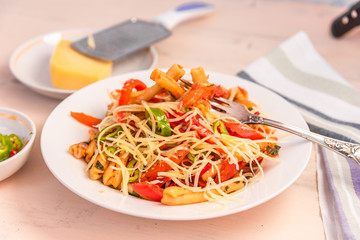 Italian food - Pasta with red pepper and parmesan on a white plate on a rustic light table