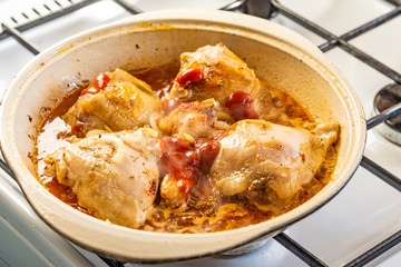 Chicken stew in a pan with onions and tomato paste close-up