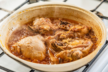 Chicken stew in a pan with onions and tomato paste close-up