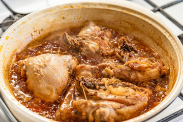 Chicken stew in a pan with onions and tomato paste close-up