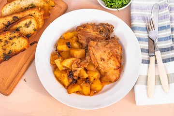 French food - chicken stew with potatoes in tomato sauce on a white plate with fried croutons, top view
