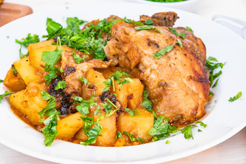 Healthy rustic food - stew chicken with potatoes in tomato sauce on a white plate, close-up