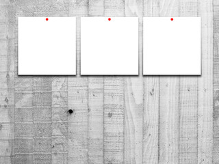 Three blank square instant photo frames with red pins on grey concrete wall background