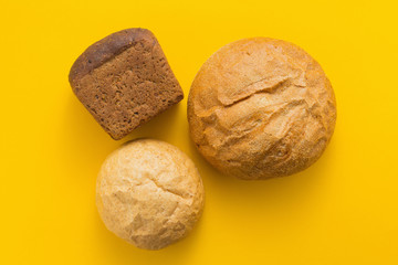 Freshly baked bread on yellow colored background, top view