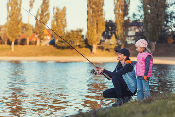 mother and daughter are fishing on the lake.