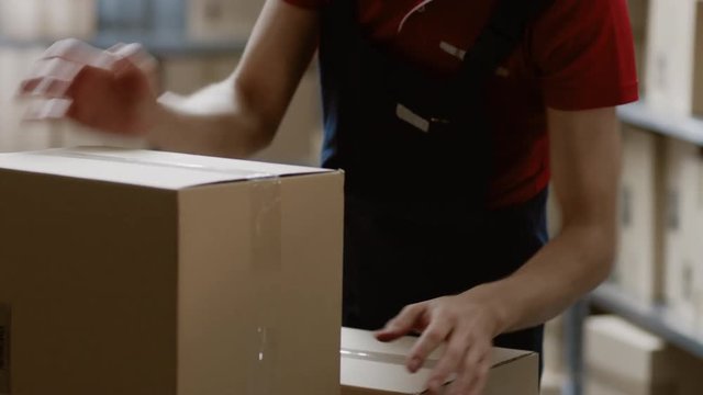 Warehouse Worker Collects Order by Taking Cardboard Boxes and Parcels of the Shelf and Putting them On a Trolley. 