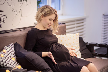 Pregnant woman is sitting on a bed on Christmas