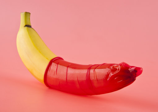 yellow banana with a red condom on a pink background