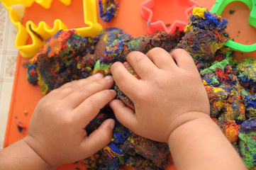 hands of child playing multicolored kinetic sand. children activity game toy for model forming...
