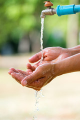 Water pouring in people hand on nature background environment issues.Health care concept.