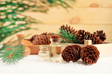 Bottles with essential aroma oil with pine cones and green fir tree branches, wooden background....
