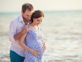 Happy young couple expecting a baby in the background of the sea. Romantic pregnancy portrait.