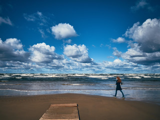 A young girl is walking along the seashore.