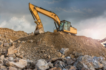 A large yellow excavator moving stone in a quarry - obrazy, fototapety, plakaty