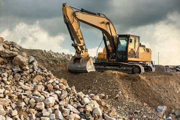 A large yellow excavator moving stone in a quarry