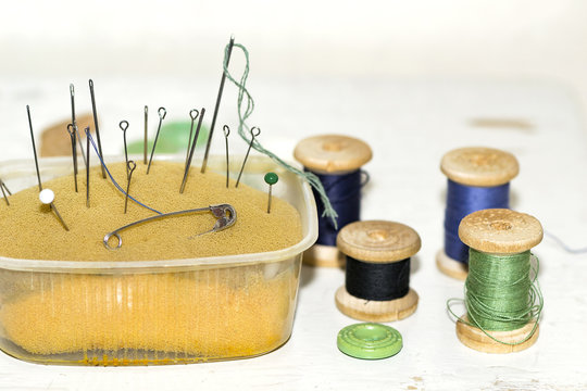 old rusty metal needles, pins in old paralon and wooden spools o