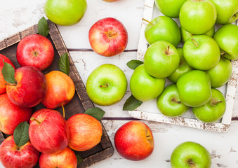 Fresh organic red and green apples in vintage box on wooden background. Top view