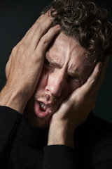 Stressful man holding his head in hands, close up