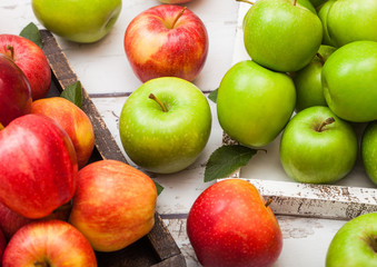 Fresh organic red and green apples in vintage box on wooden background. Top view