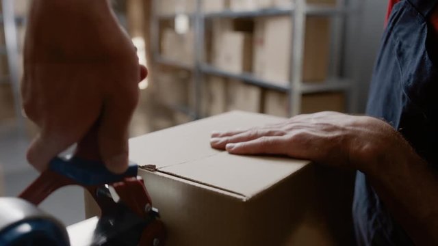 Warehouse Worker Checks and Sealing Cardboard Box Ready for Shipment. 