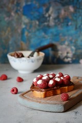 Delicious toast with Ricotta cheese chocolate and raspberries, decorated with mint leaves on vintage cutting board 