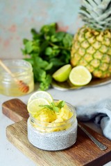 Breakfast table with Chia fruit smoothies bowl with pieces of pineapple, lime, honey and mint leaves.Healthy food. Top view, blank space