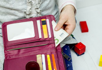 Kid is stealing money from mothers wallet. Holding money in its hand concept.