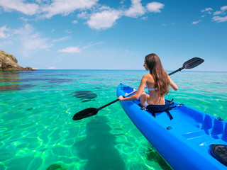 Beautiful young woman kayaking in the sea near the islands. Adventure by kayak.