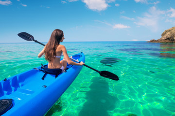 Beautiful young woman kayaking in the sea near the islands. Adventure by kayak.