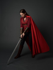  full length portrait of brunette girl wearing red medieval costume and cloak. standing pose ...