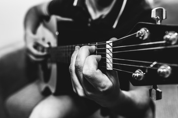 Man at home is playing the guitar. Guys hands are taking the chord on strings. Music making...
