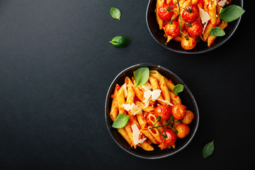Tasty tomato pasta in bowl on dark