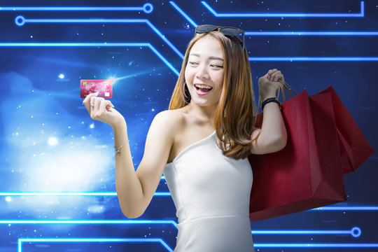Pretty asian woman with shopping bags showing her credit card