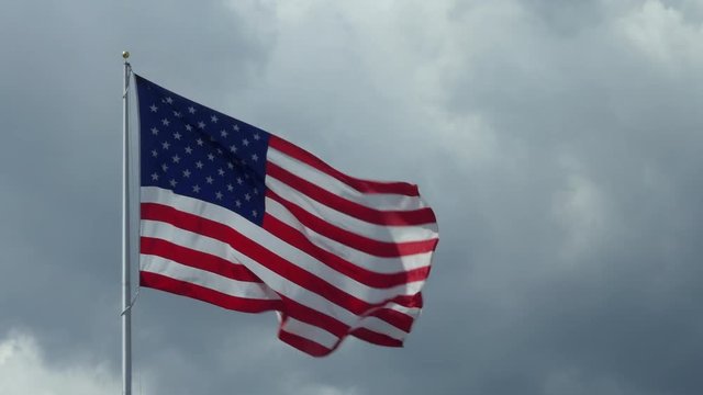 US flag flying with cloudy sky in the background. Stars and Stripes of the United States of America, symbol and concept of American freedom, liberty, democracy. Copy space