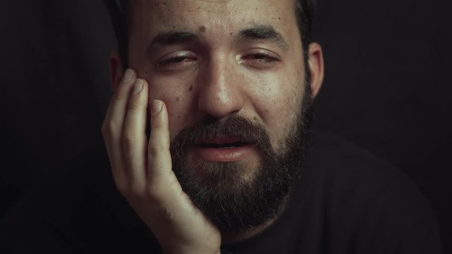 close up on young latin man crying in the dark. sadness, depression