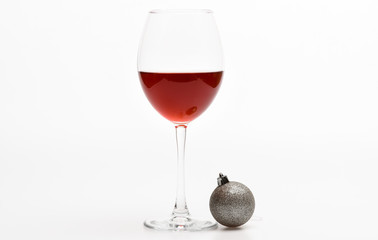 New year party concept. Glass with wine and christmas decoration. Winter celebration with alcohol drink. Wineglass with red liquid or wine and christmas ball ornament isolated on white background