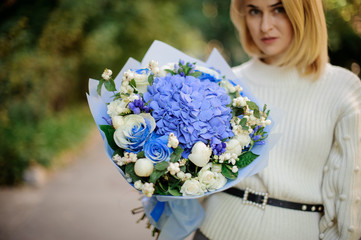 Blonde girl holding bouquet of tender blue flowers