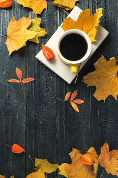 Yellow coffee mug with autumn leaves on a dark wooden table. Copy space