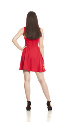 back view of young woman in short red dress and high heels on white background
