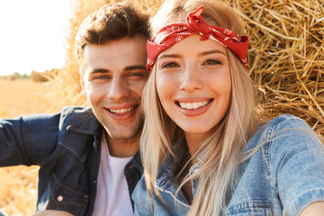 Close up of a happy young couple sitting at the wheat field