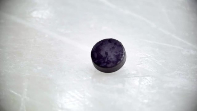 Hand rotates the black puck on the ice hockey field