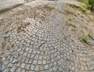Old ruin coblestone road. Granite cobblestoned pavement