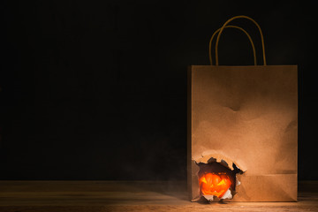 halloween pumpkin in tearing of craft paper bag, black background