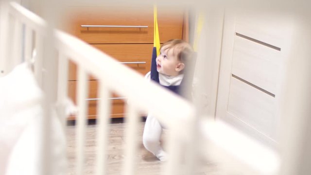 happy little baby playing, jumping in children's room and laughing