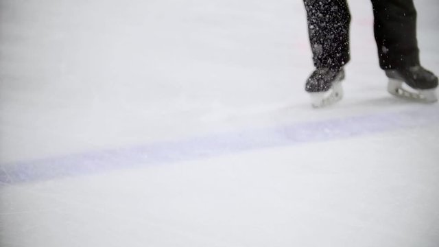 Hockey player rides backwards and slows down on the ice of a hockey field, scratching the ice
