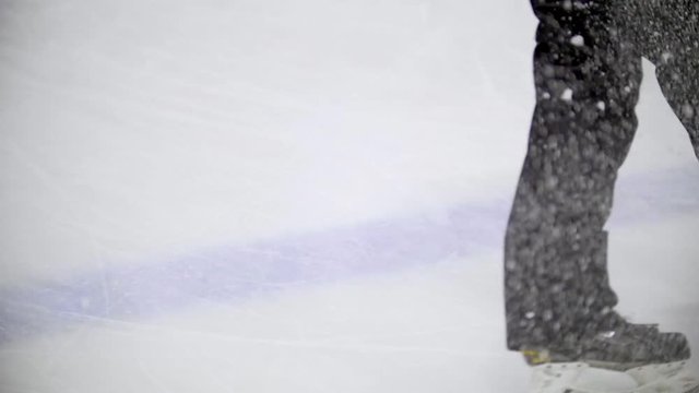 Hockey player rides backwards and slows down on the ice of a hockey field, scattering ice particles