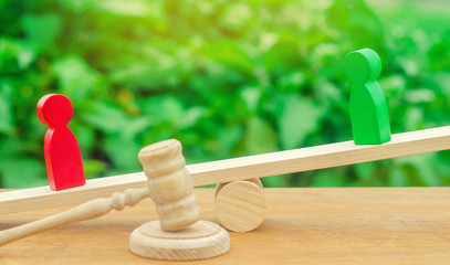 wooden figures of people. rivals in business stand on the scales. trial. conflict. victory and...
